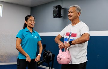 A Stirling Leisure instructor guiding a senior male with weights